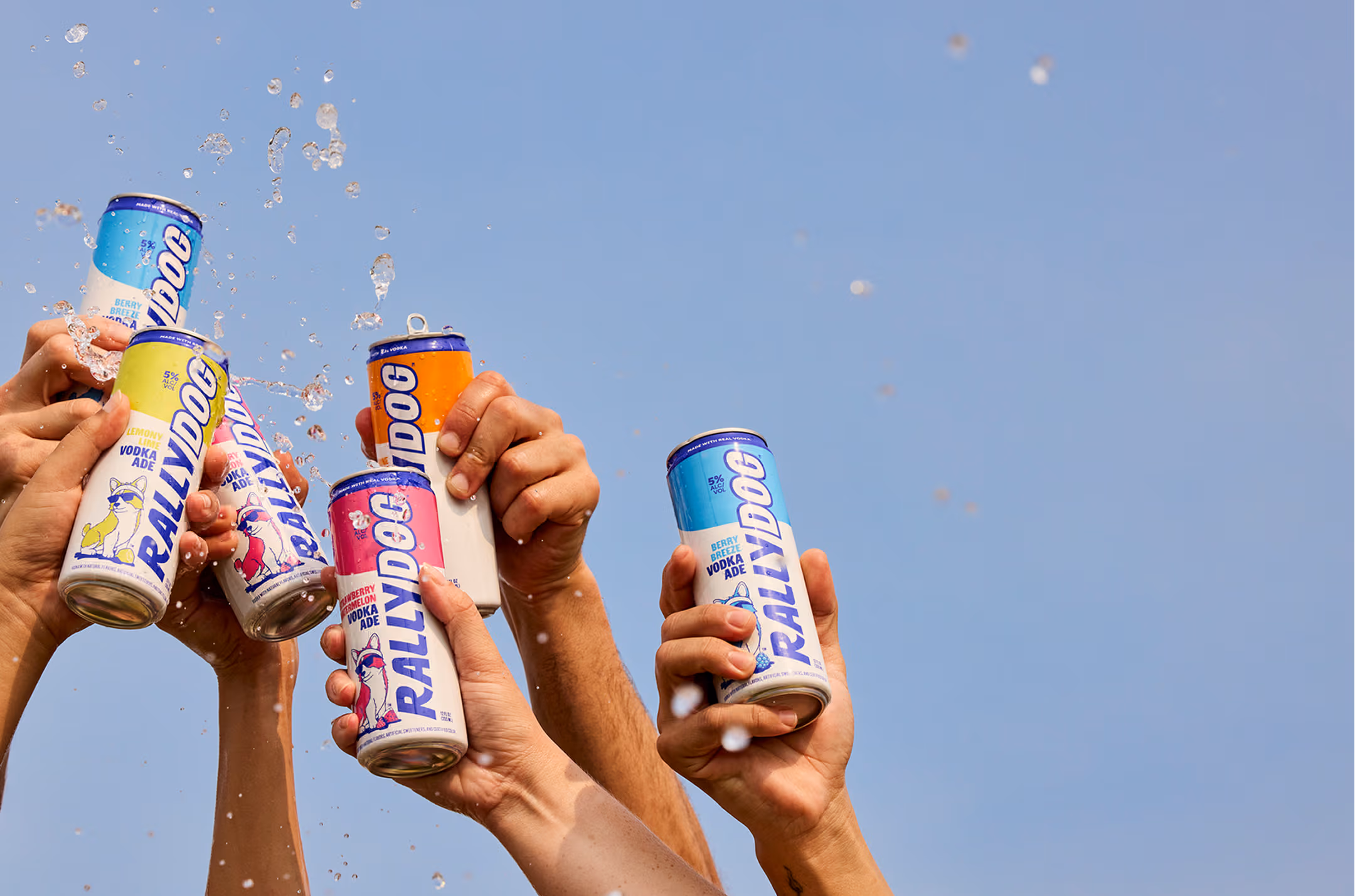 Several hands cheersing with cans of Rally Dog Vodka Ade