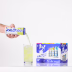 A hand pouring Rally Dog Lemony Lime Vodka Ade into a glass