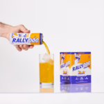 A hand pouring Rally Dog Tangerine Twist Vodka Ade into a glass